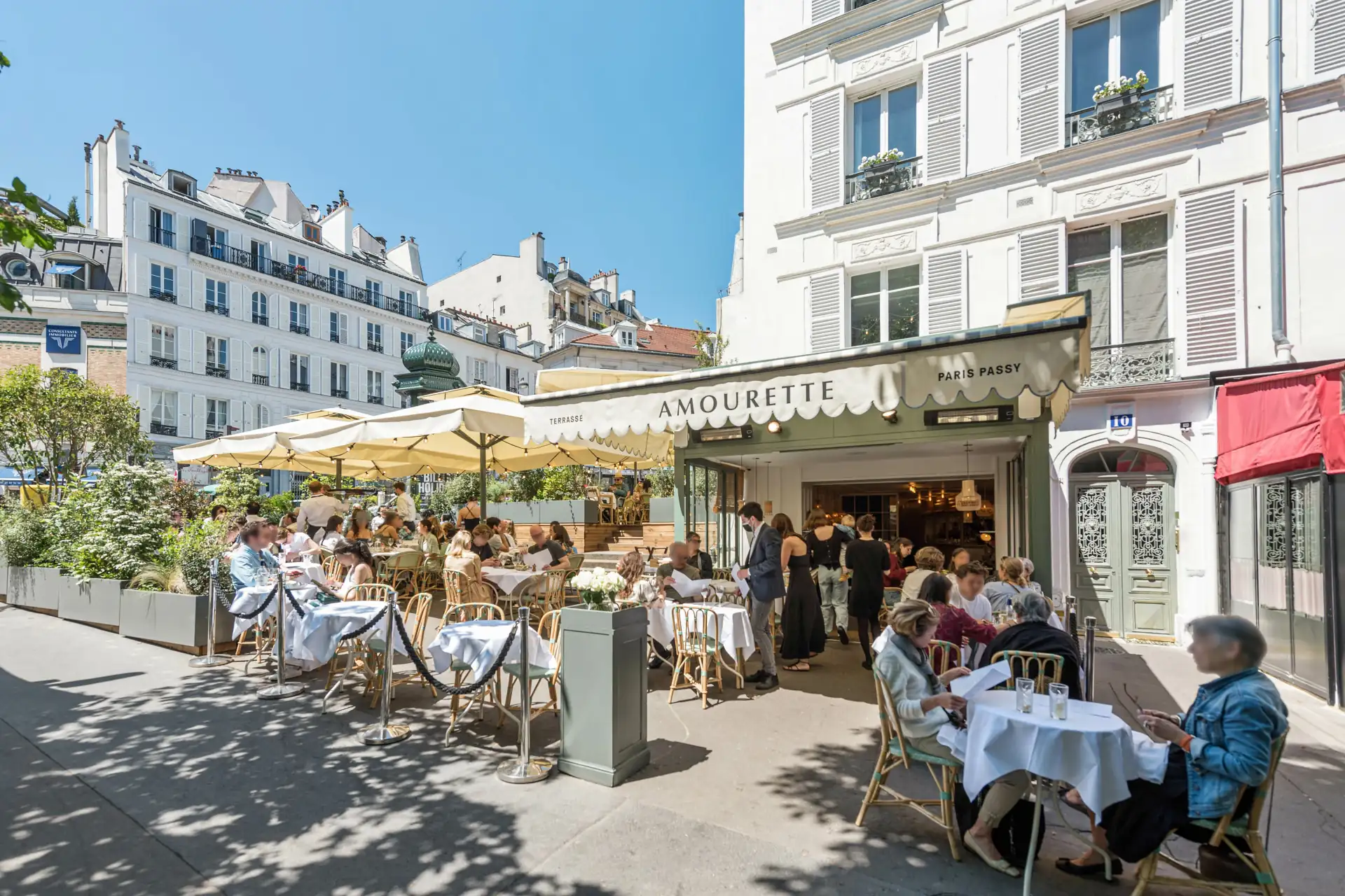 Amourette Passy terrace with guests seated under lime trees on Boulevard Delessert